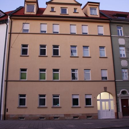 Mehrgeschossiges Wohnhaus mit heller Fassade und weißen Fenstern in gleichmäßiger Anordnung.