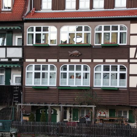 Traditionelle Fachwerkfassade mit weißen Fenstern und Fischornament zwischen den oberen Fensterreihen.