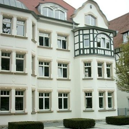 Mehrstöckiges Wohnhaus mit weißen Holzfenstern und Erker, saniert im klassischen Stil mit hellem Putz und dezentem Fassadenschmuck.