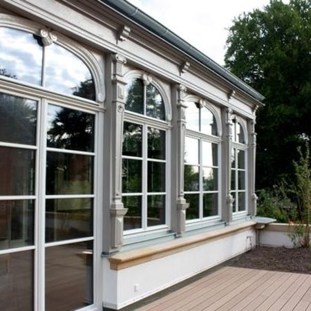 Sanierte historische Fensterfront mit mehrfach verglasten Rundbogenfenstern und reich verzierter Stuckfassade im Außenbereich.