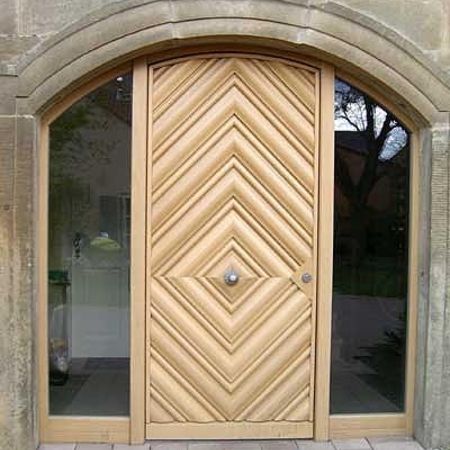 Massive Holztür mit Fischgrätmuster: Moderne Haustür aus hellen Holzleisten in auffälligem Fischgrätmuster, eingefasst in Segmentbogen und flankiert von Glasfeldern.