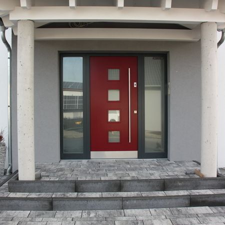 Moderne rote Eingangstür mit Glaselementen: Zeitgenössische, rote Haustür mit vier quadratischen Glasfeldern und seitlichem Glaselement in grauer Putzfassade.