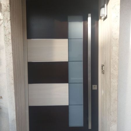 Designhaustür mit Holz- und Glaselementen: Tür mit horizontalen Holz- und Glaseinsätzen im Wechsel, kombiniert mit einem langen vertikalen Edelstahlgriff.