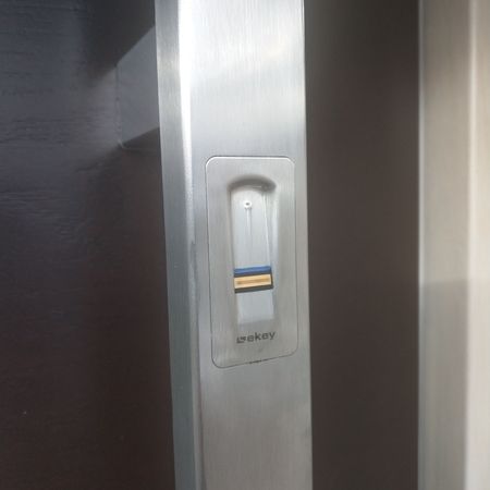 In einen silberfarbenen Haustürgriff integrierter Fingerprint-Scanner mit farbigen Markierungen, Modell „ekey“.